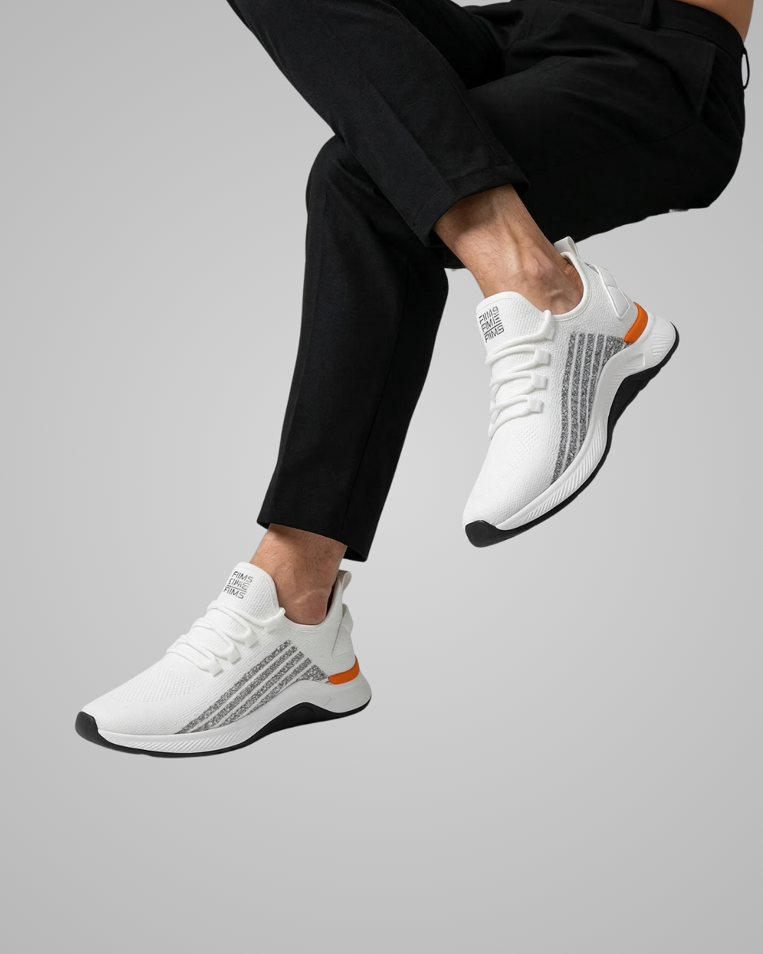 Person wearing white sneakers with orange accents on a gray background