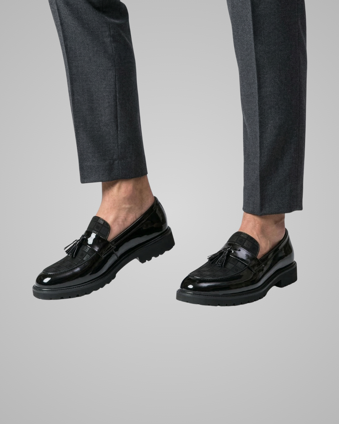 Black loafers worn with gray pants on a light gray background
