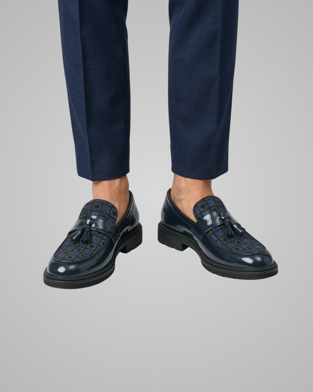 Navy loafers worn with dark blue pants on a light gray background