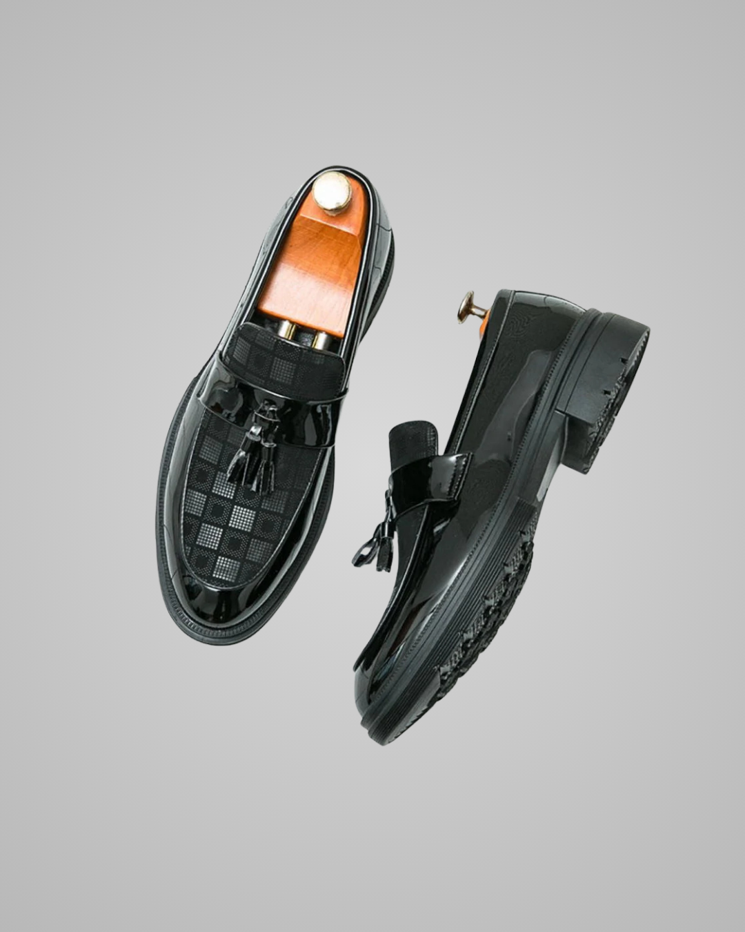 Black loafers with a checkered sole on a gray background