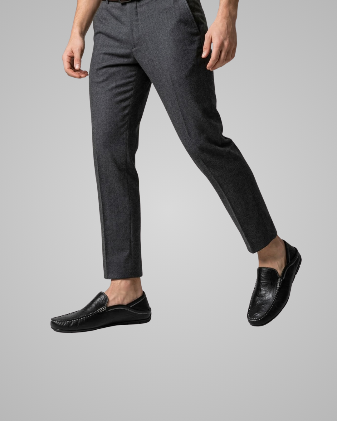 Person wearing gray pants and black loafers on a light gray background