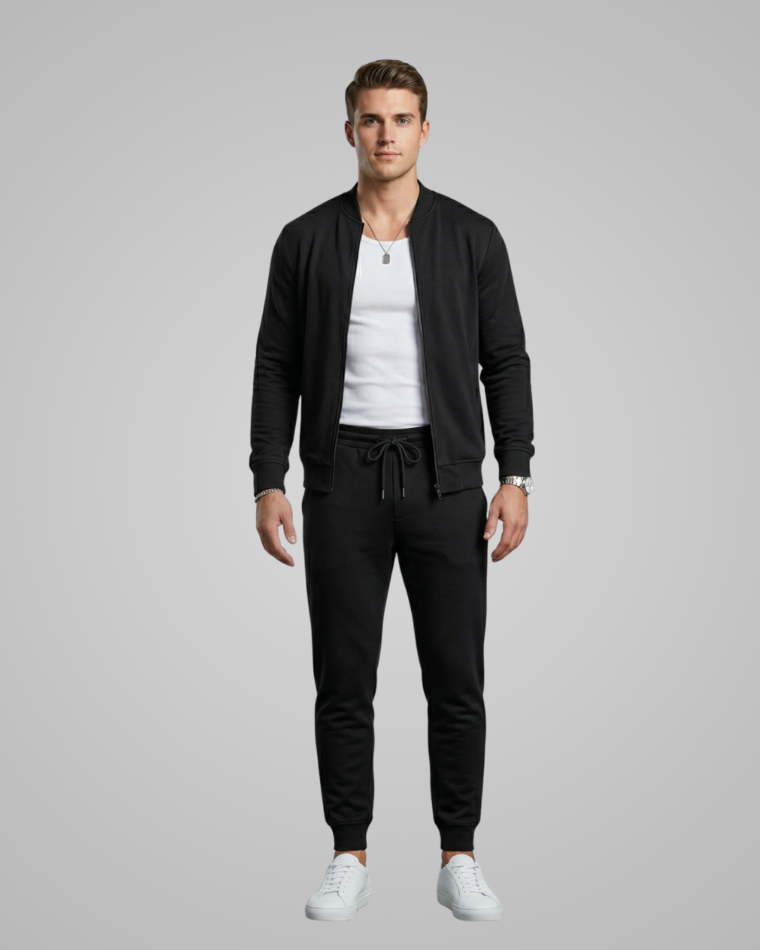 Man wearing a black tracksuit with a white shirt underneath on a gray background