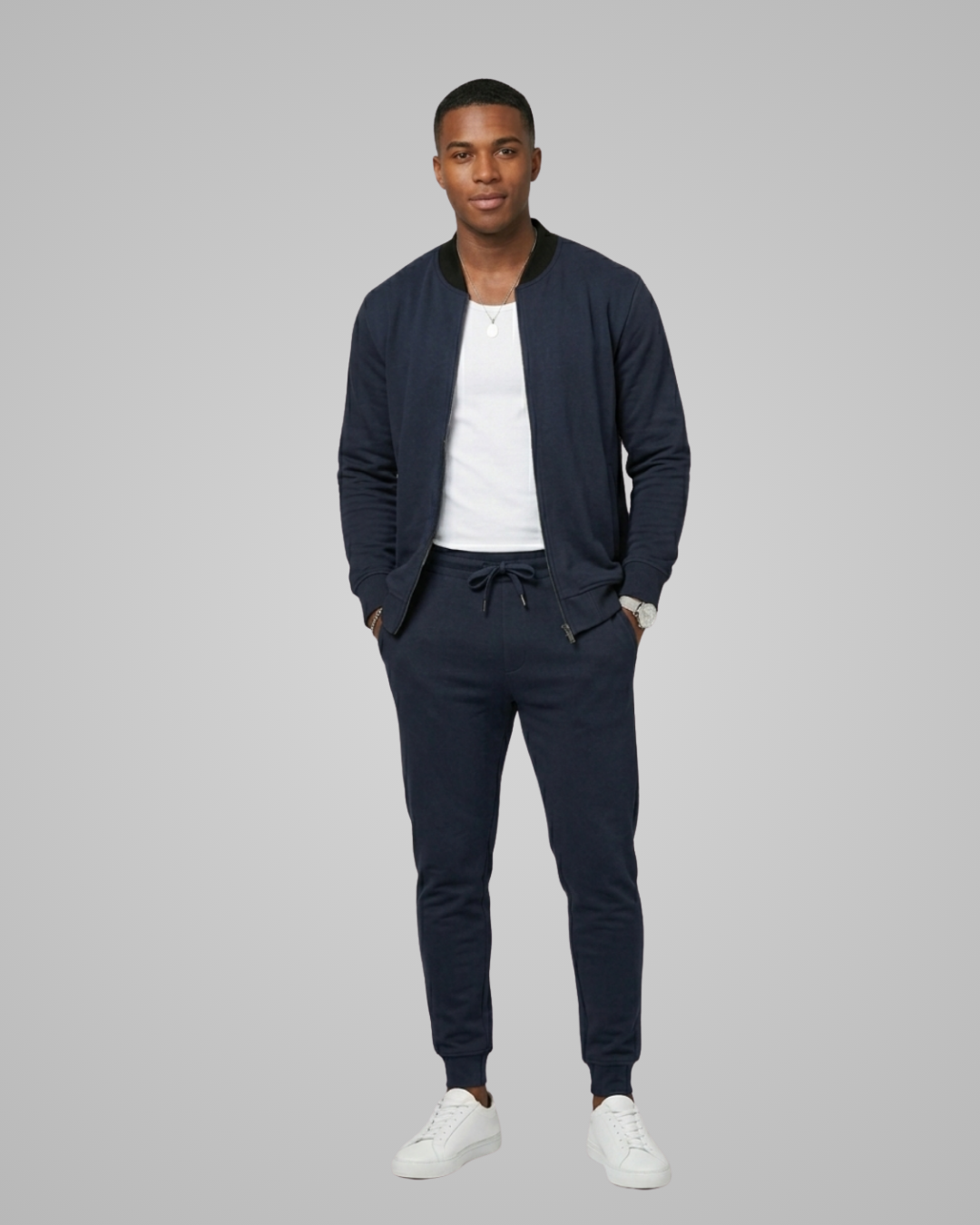 Man wearing a navy tracksuit with a white shirt on a gray background