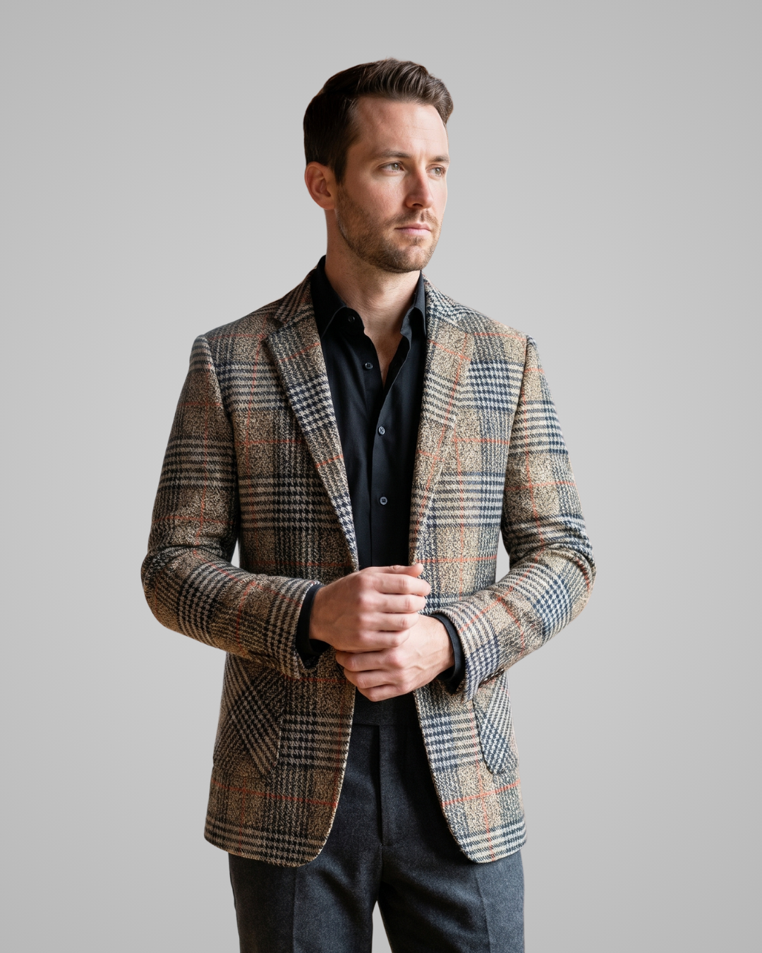 Man wearing a patterned blazer over a black shirt on a gray background