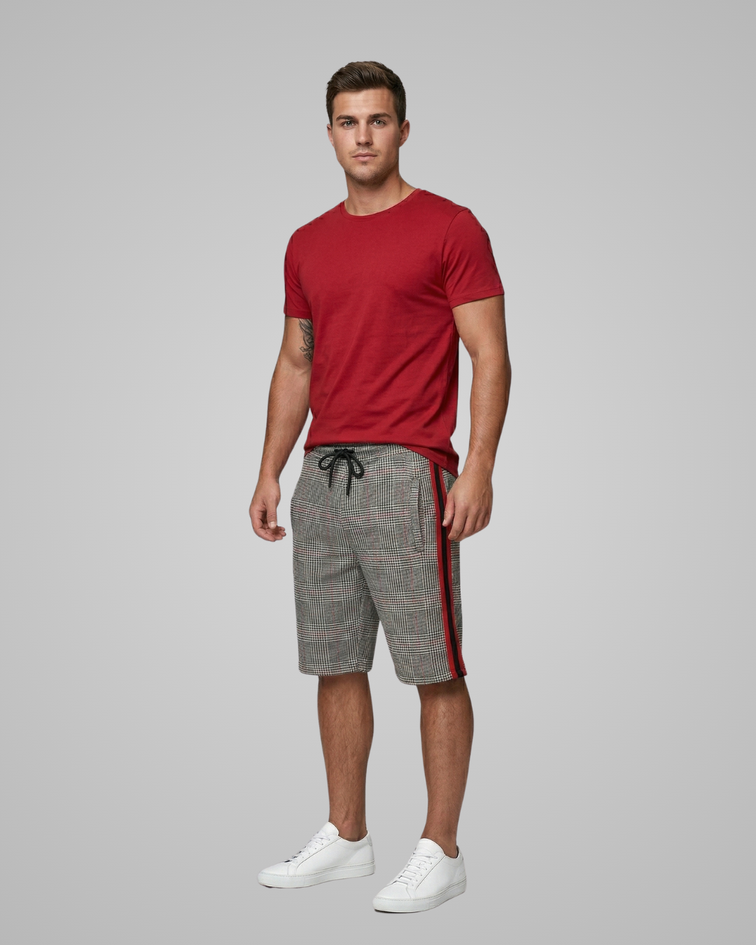 Man wearing a red t-shirt and gray shorts with a red stripe on a gray background