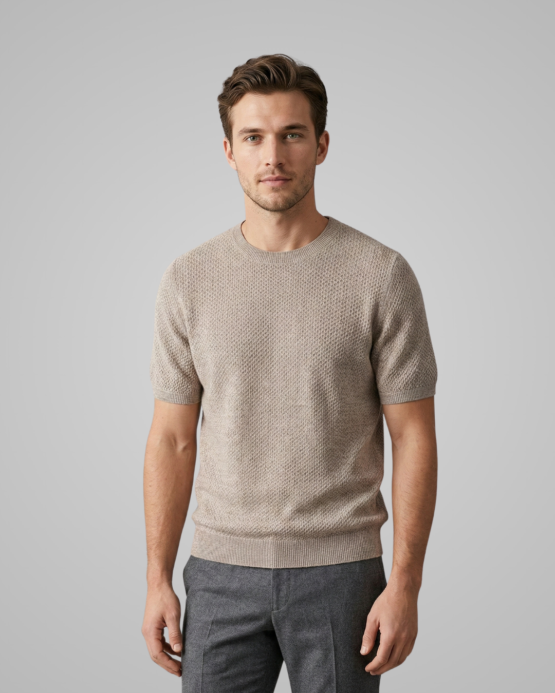 Man wearing a beige short-sleeve sweater against a gray background