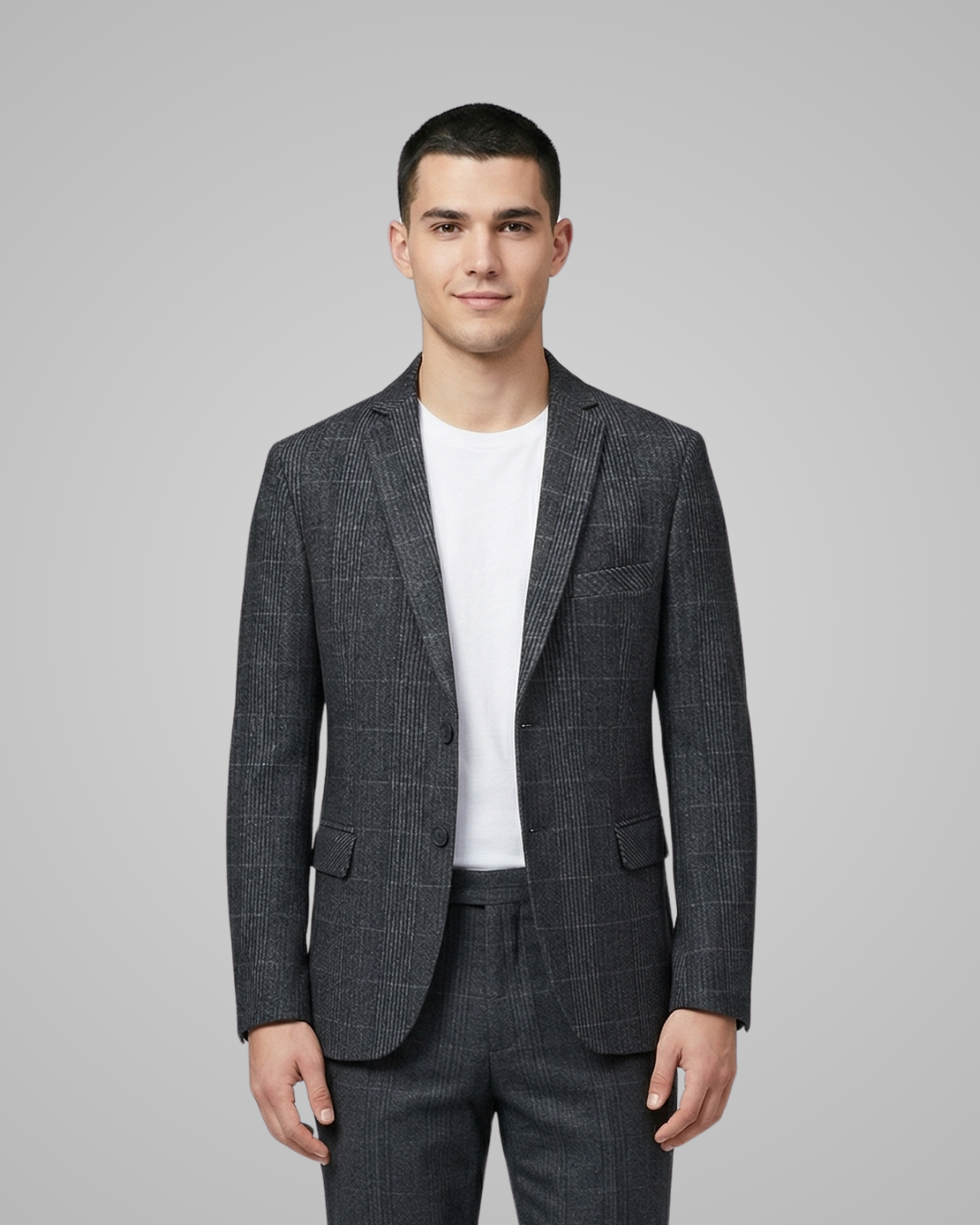 Man wearing a gray checkered suit jacket over a white shirt on a gray background