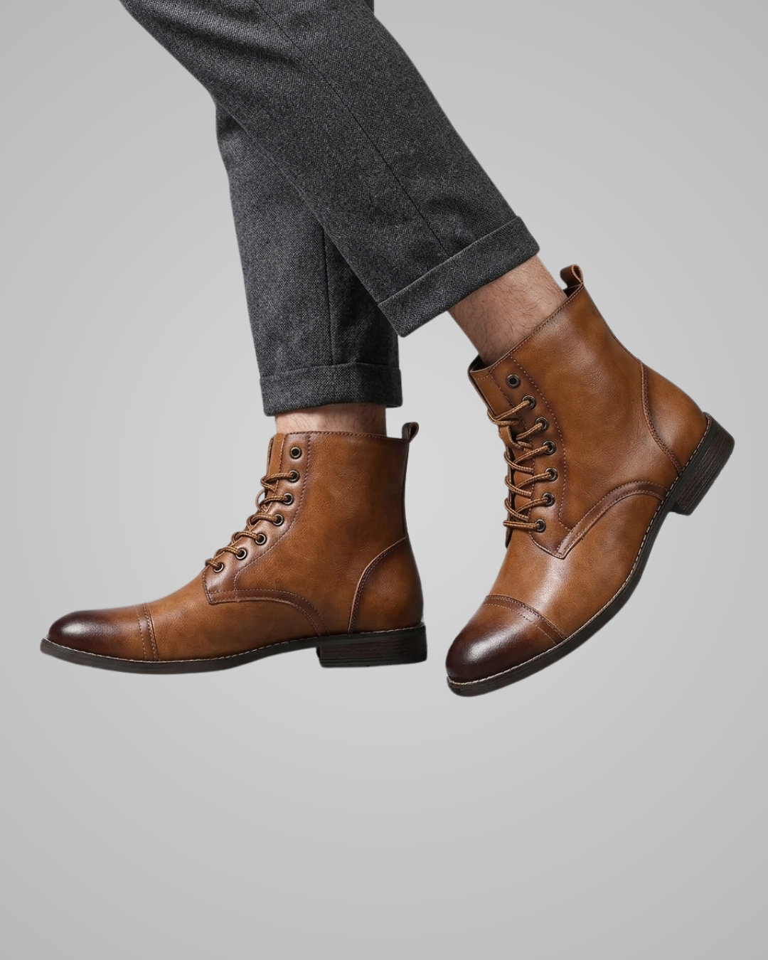 Brown leather boots worn with gray pants on a light gray background