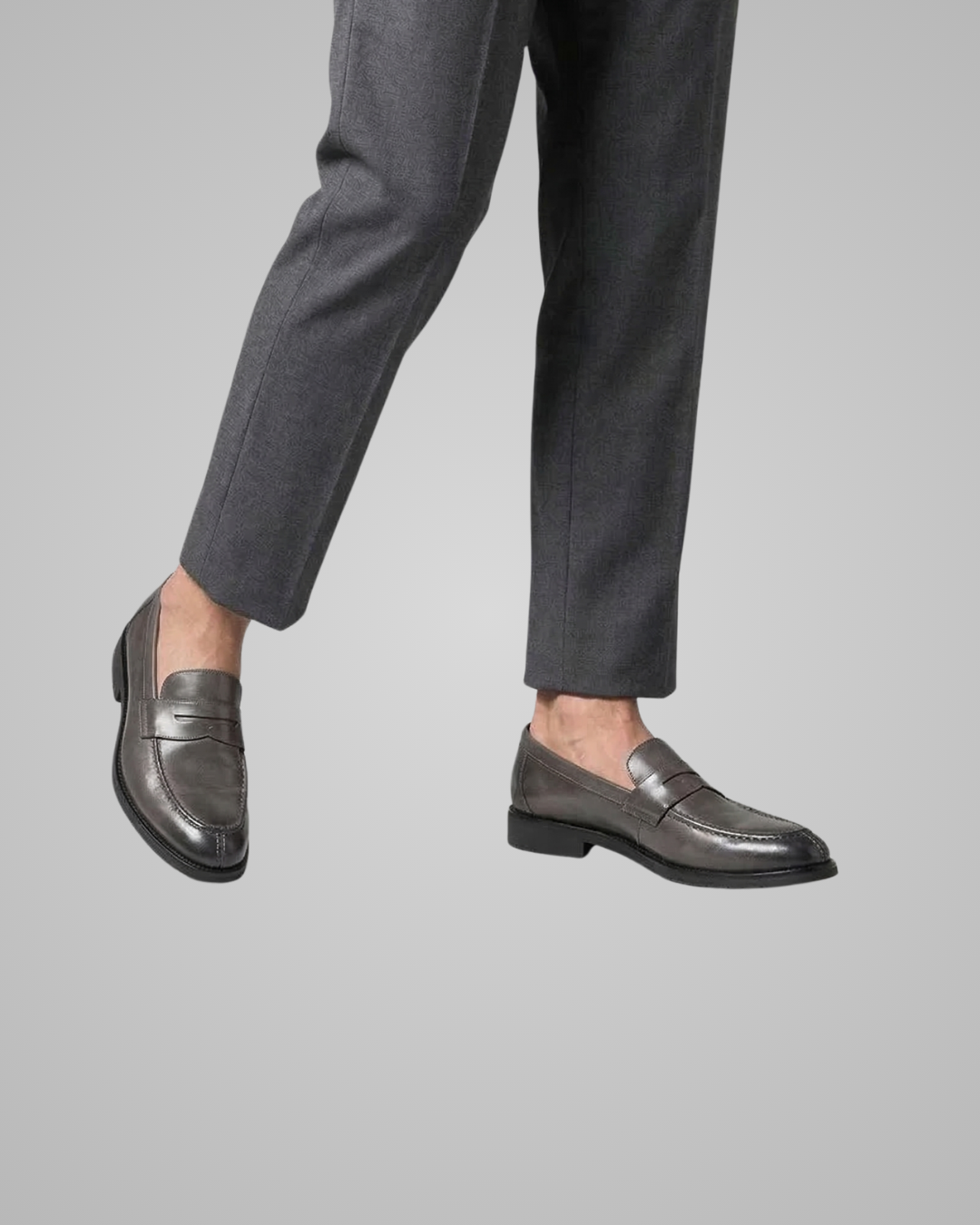 Gray loafers worn with dark gray pants on a light gray background