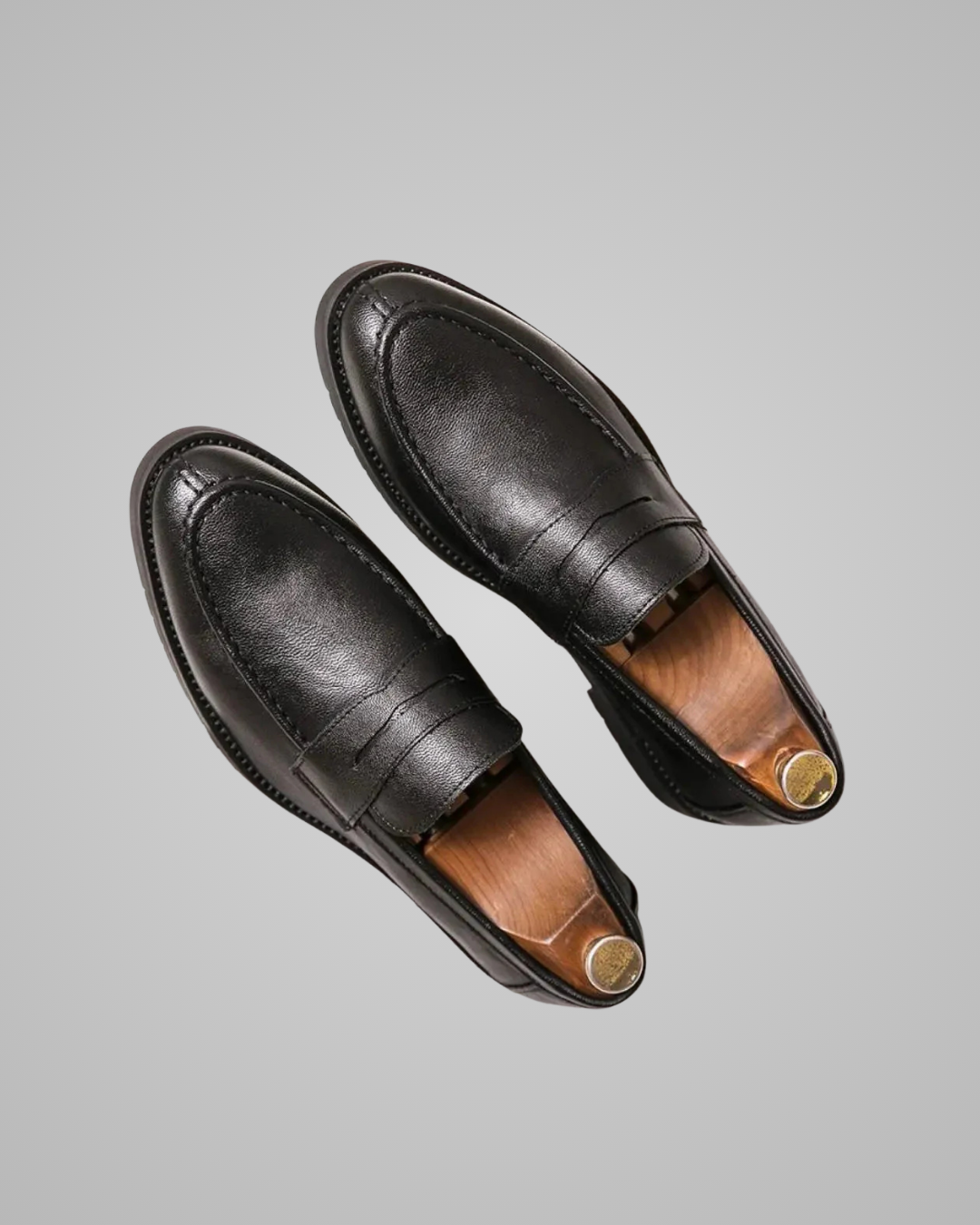 Pair of black leather loafers on a gray background