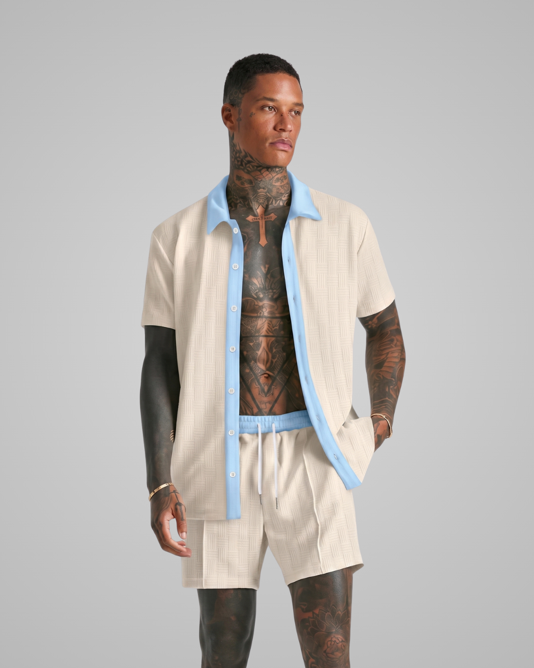 Man wearing a apricot outfit with tattoos on a gray background