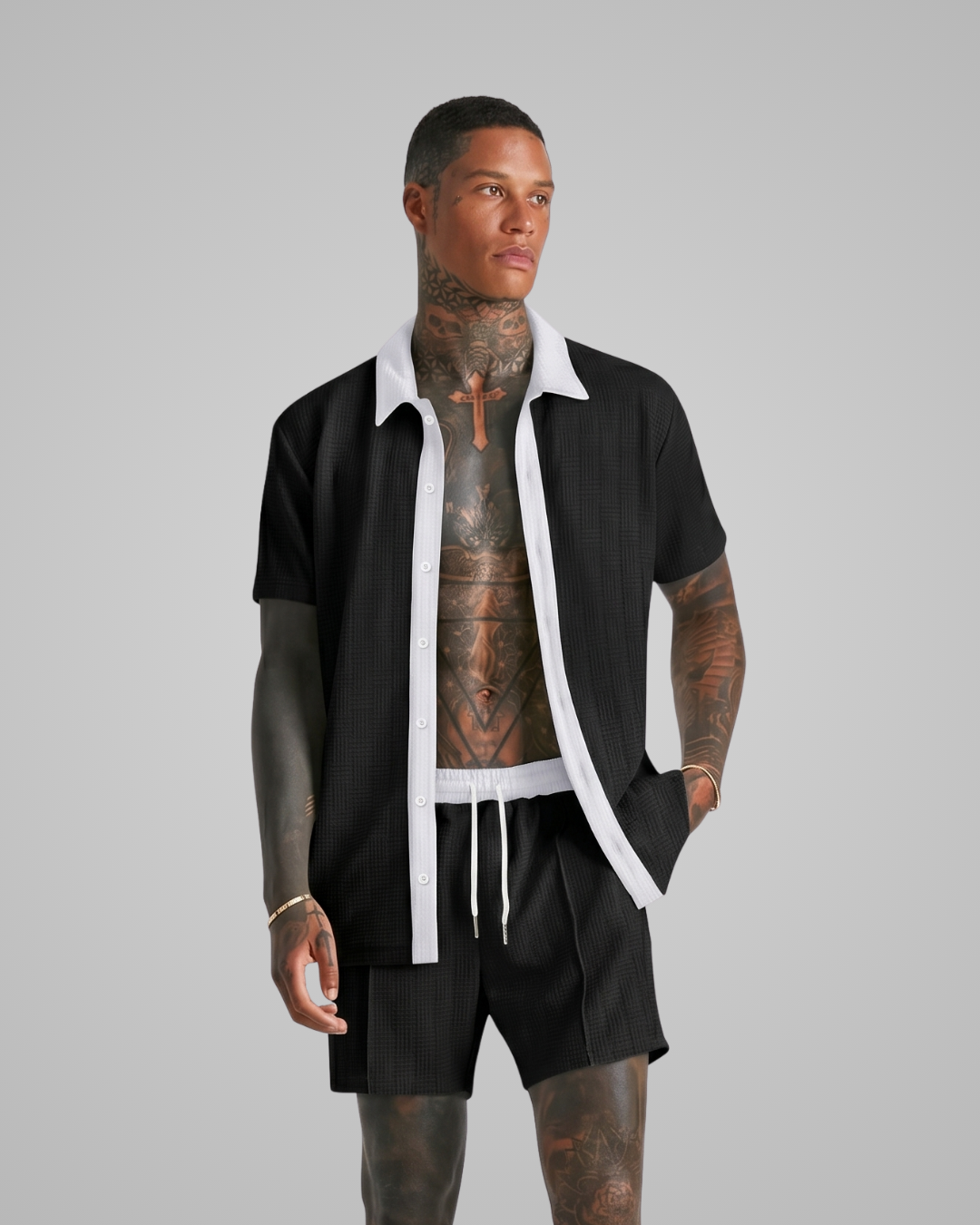 Man wearing a black outfit with tattoos on a gray background