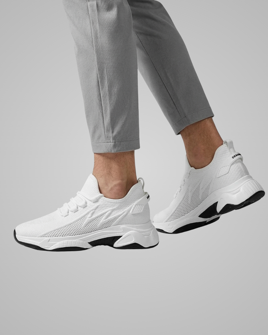 White sneakers worn with gray pants on a light gray background