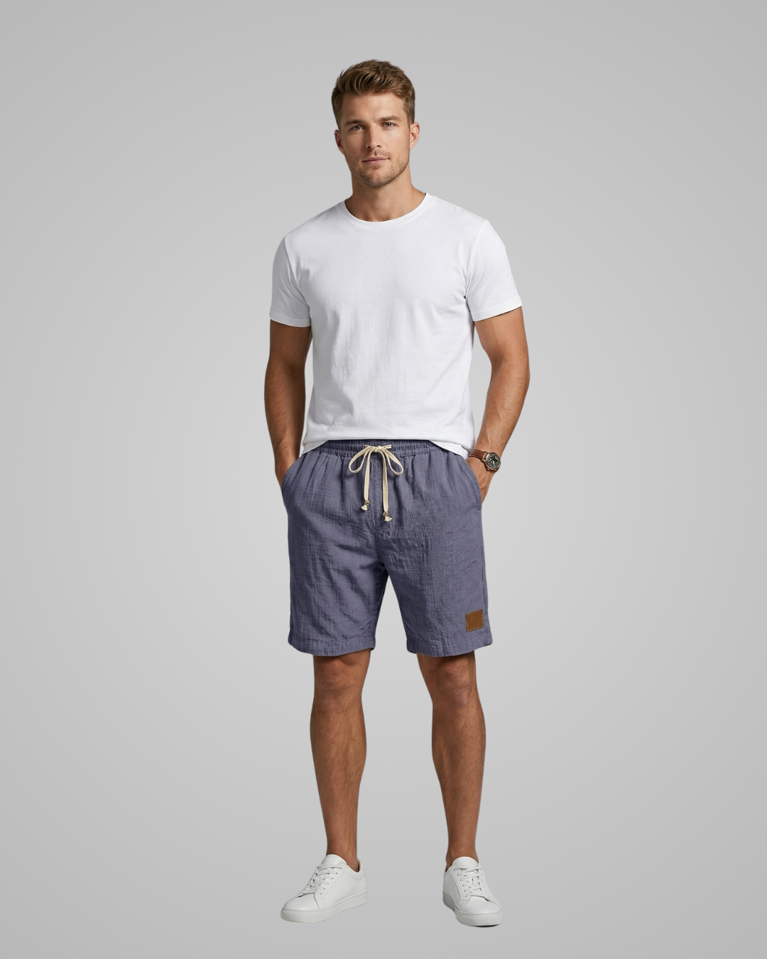 Man wearing a white t-shirt and blue shorts on a gray background