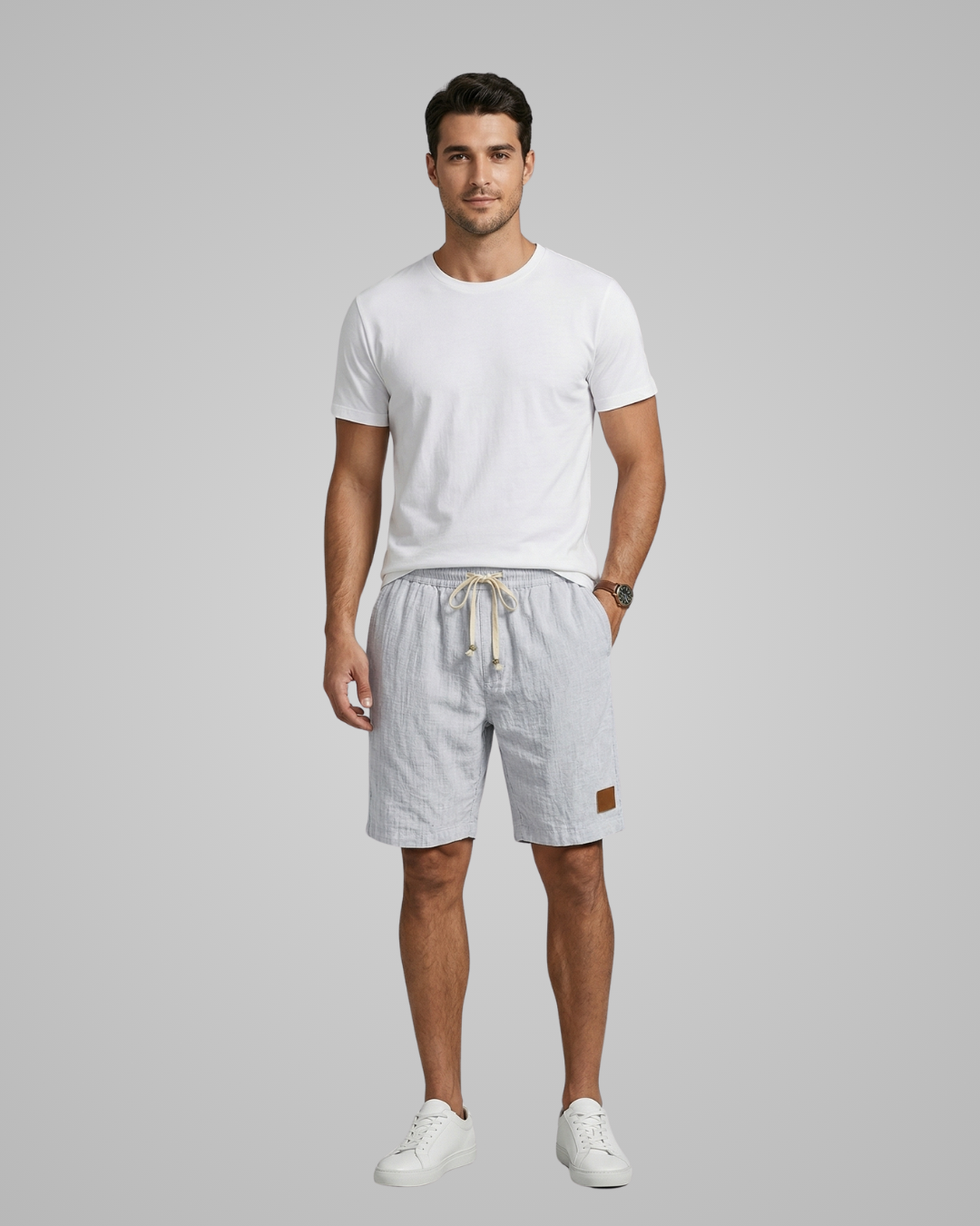 Man wearing a white t-shirt and light gray shorts on a gray background