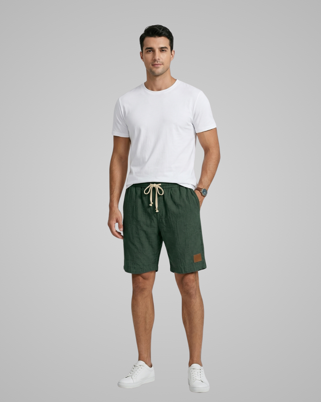 Man wearing a white t-shirt and green shorts on a gray background