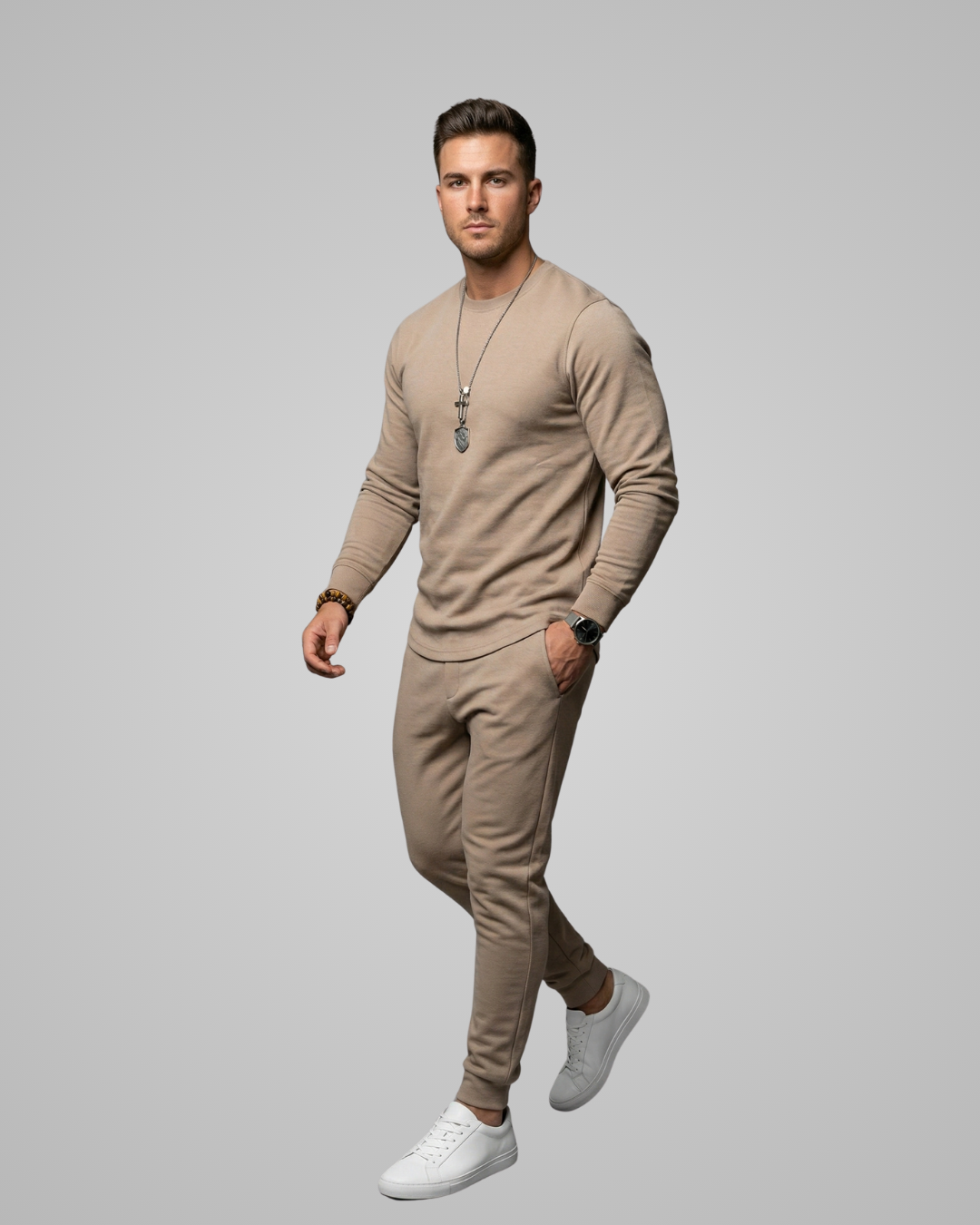 Man wearing a beige outfit with white sneakers on a gray background