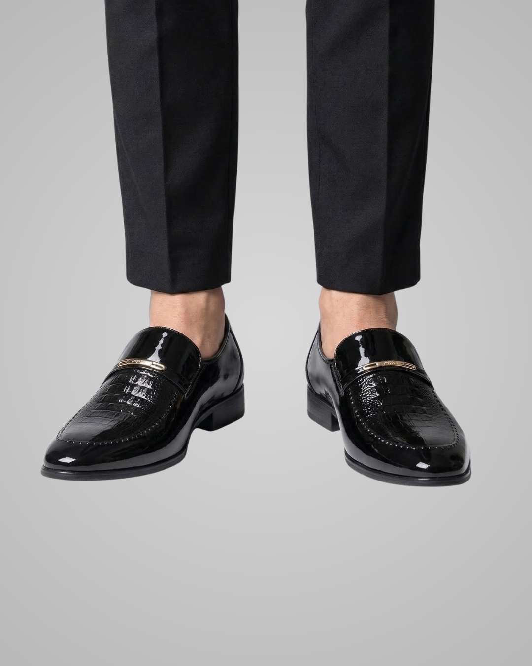 Black dress shoes worn with black pants on a gray background