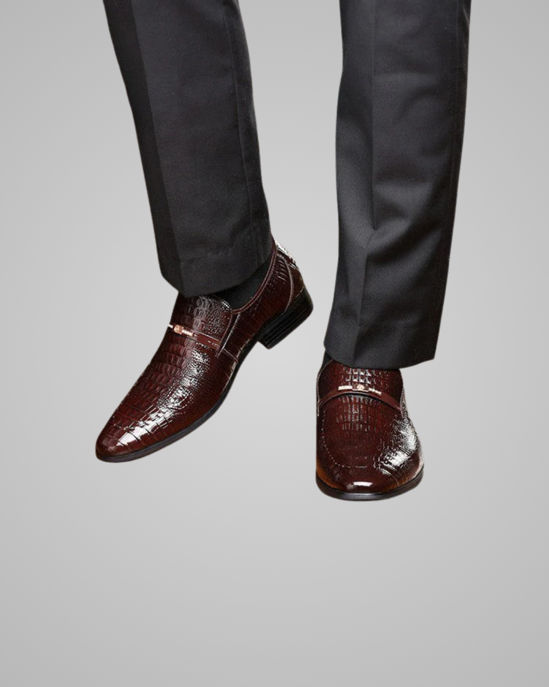 Brown dress shoes worn with dark gray pants on a light gray background