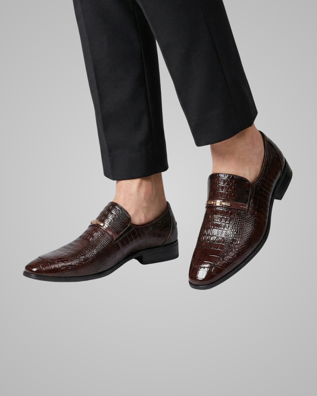 Brown dress shoes worn with black pants on a gray background