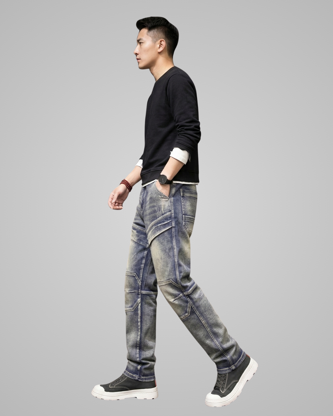 Man wearing a black sweater and gray jeans on a gray background