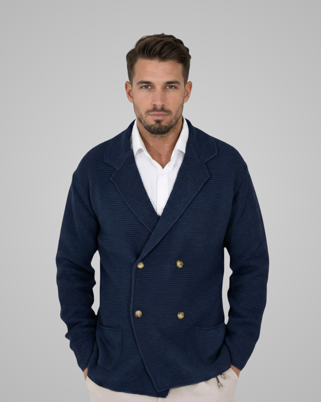 Man wearing a navy blazer with gold buttons on a gray background