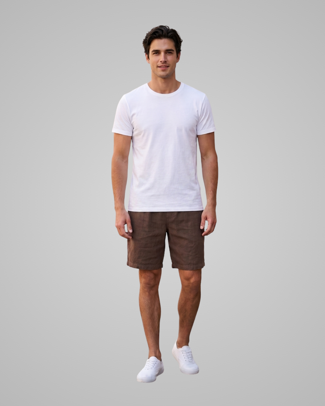 A man modeling a white short-sleeve crewneck t-shirt and brown shorts against a solid gray studio background.