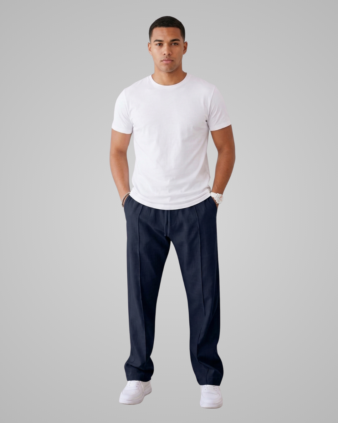 Man wearing a white t-shirt and navy pants on a gray background