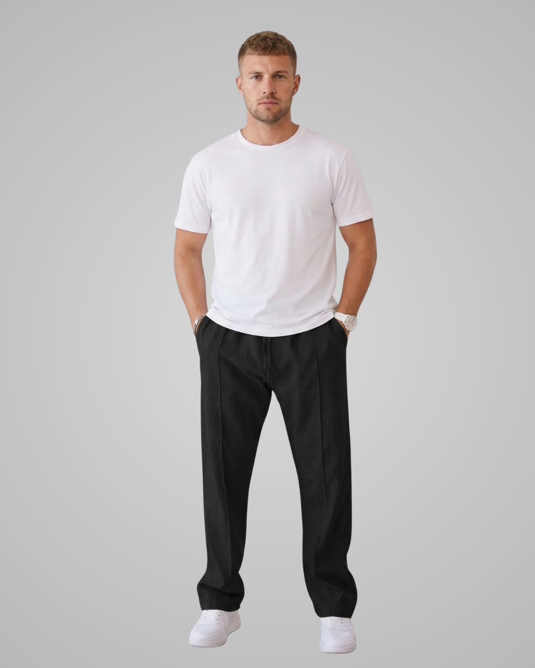 Man wearing a white t-shirt and black pants on a gray background