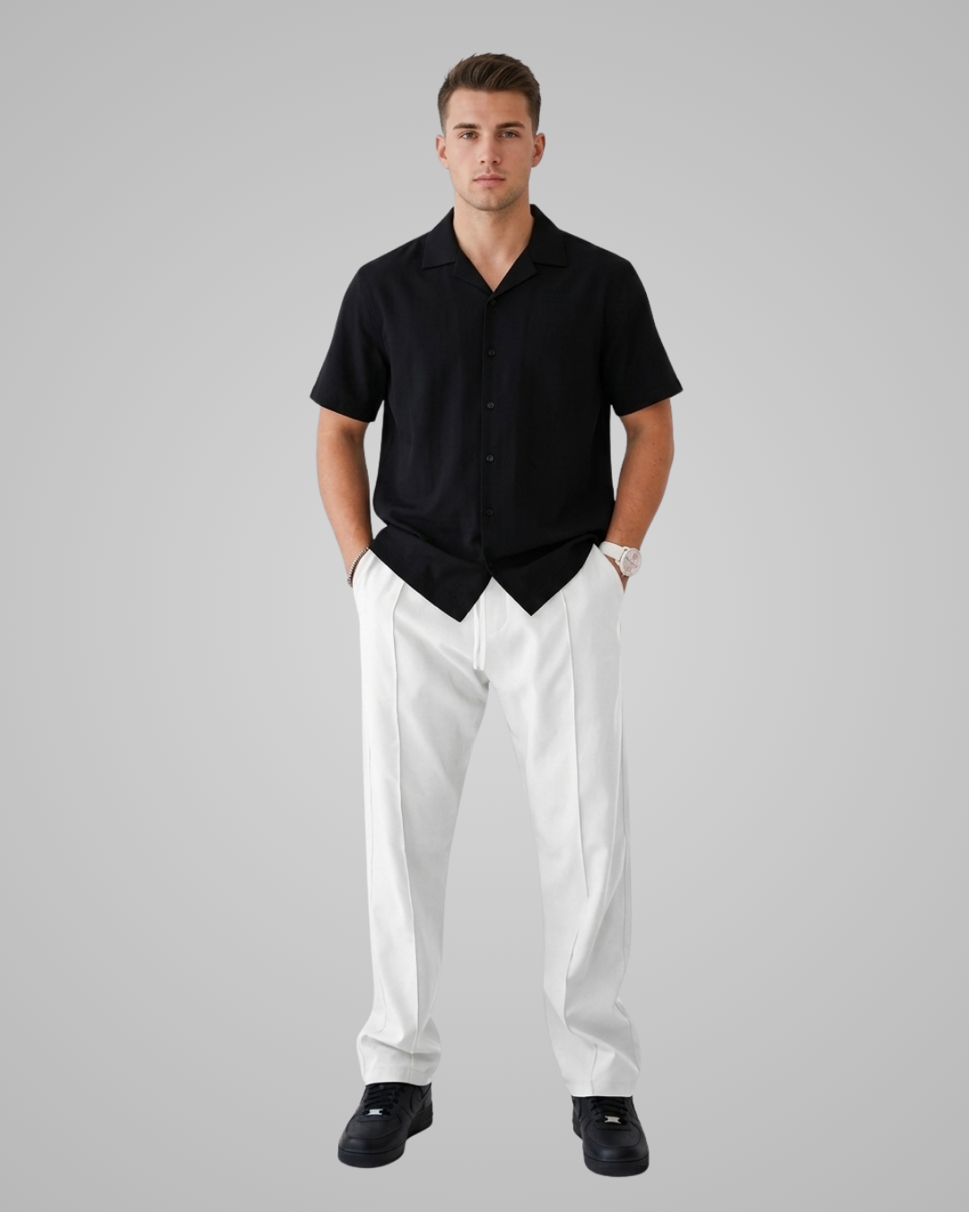 Man wearing a black shirt and white pants on a gray background