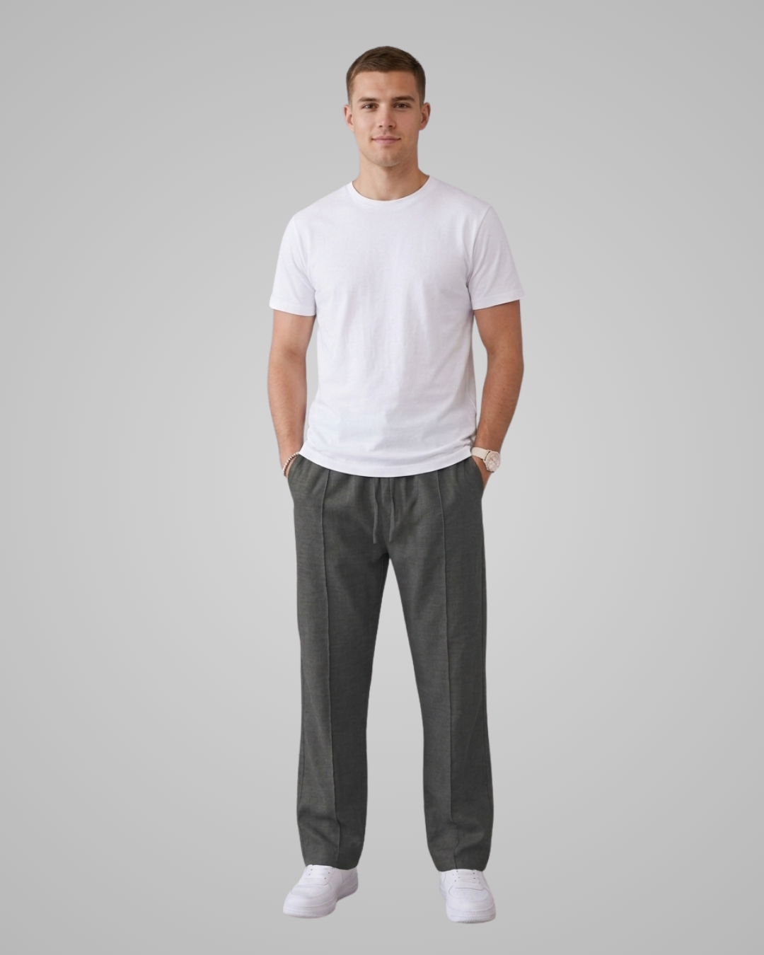 Man wearing a white t-shirt and gray pants on a plain background