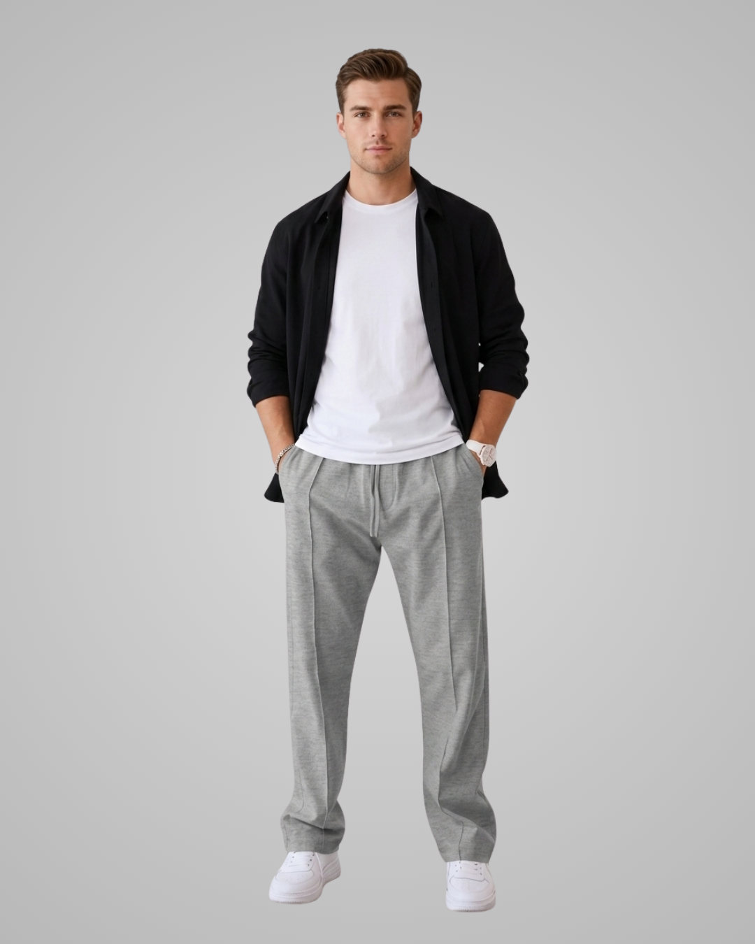 Man wearing a black jacket, white t-shirt, gray pants, and white socks on a gray background