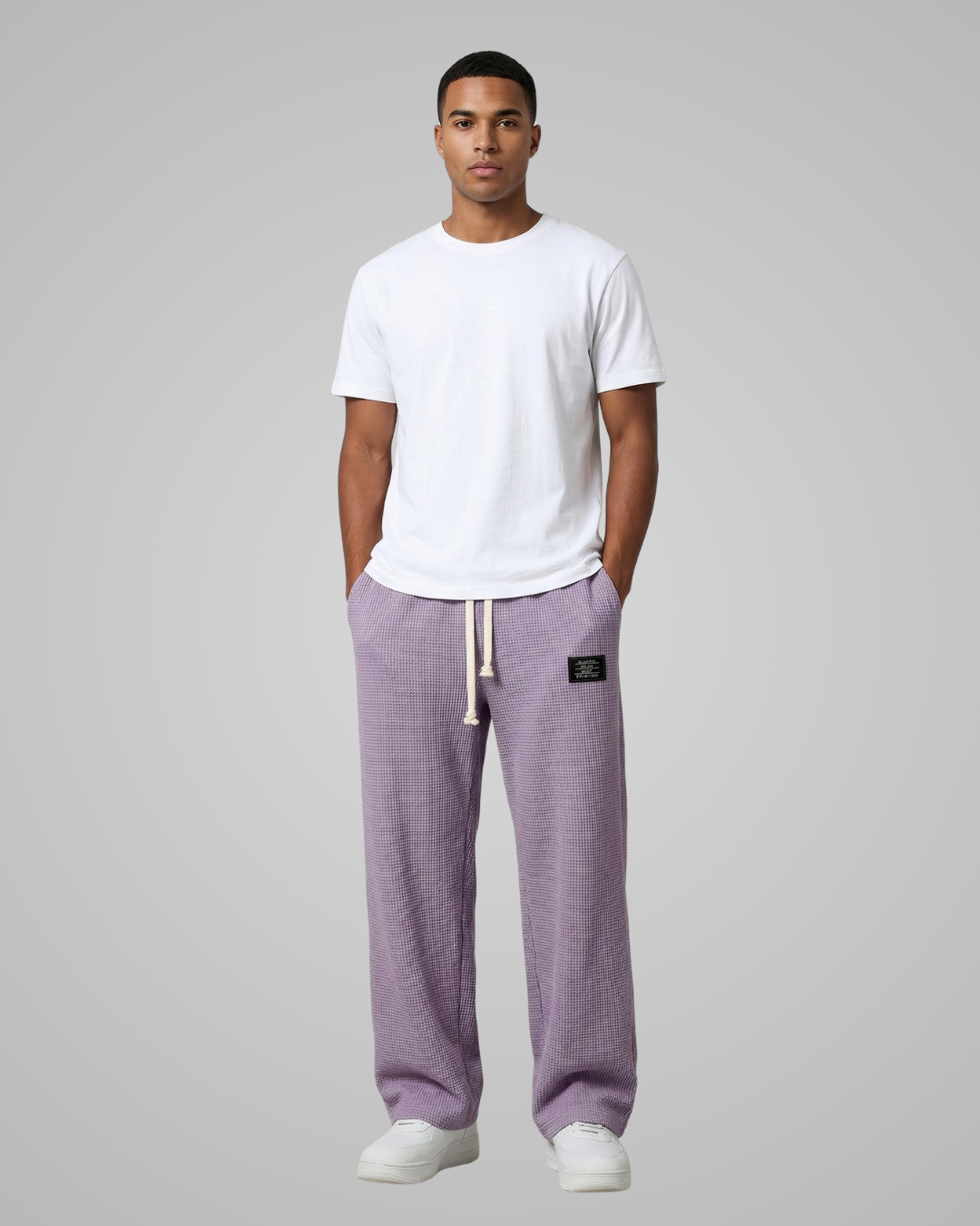 Man wearing a white t-shirt and purple sweatpants on a gray background