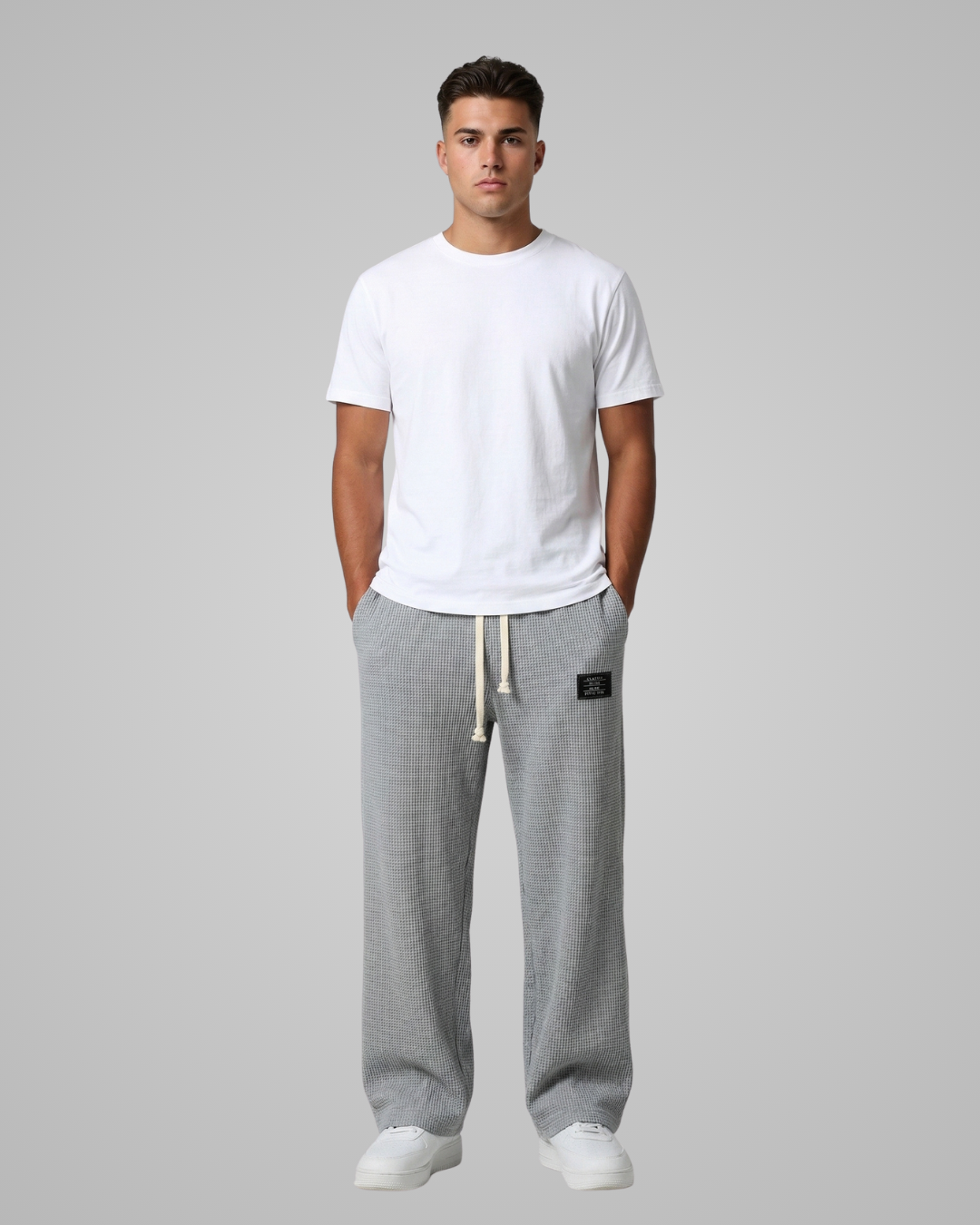 Man wearing a white t-shirt and gray sweatpants on a plain background