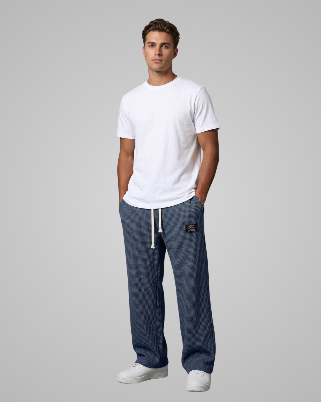 Man wearing a white t-shirt and blue pants on a gray background