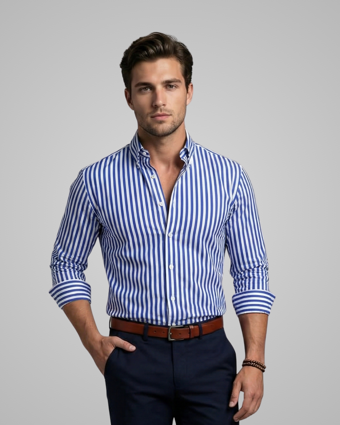 Man wearing a blue and white striped shirt with navy pants on a gray background