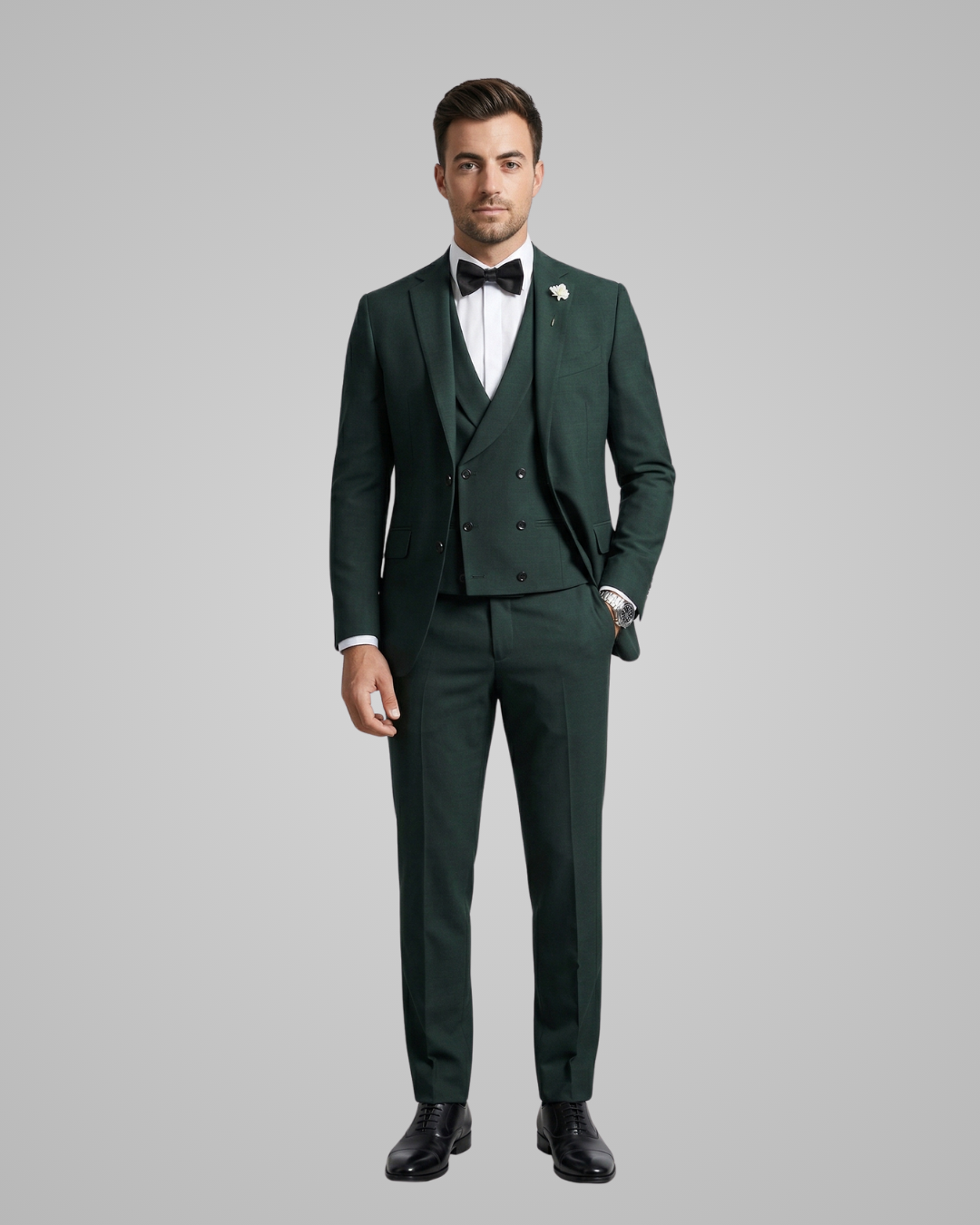 Man wearing a dark green suit with a white shirt and black bow tie on a gray background