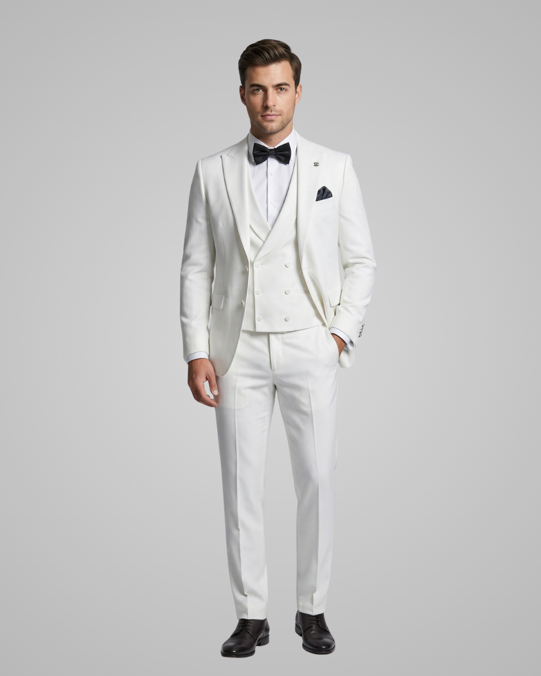 Man wearing a white tuxedo with a black bow tie on a gray background