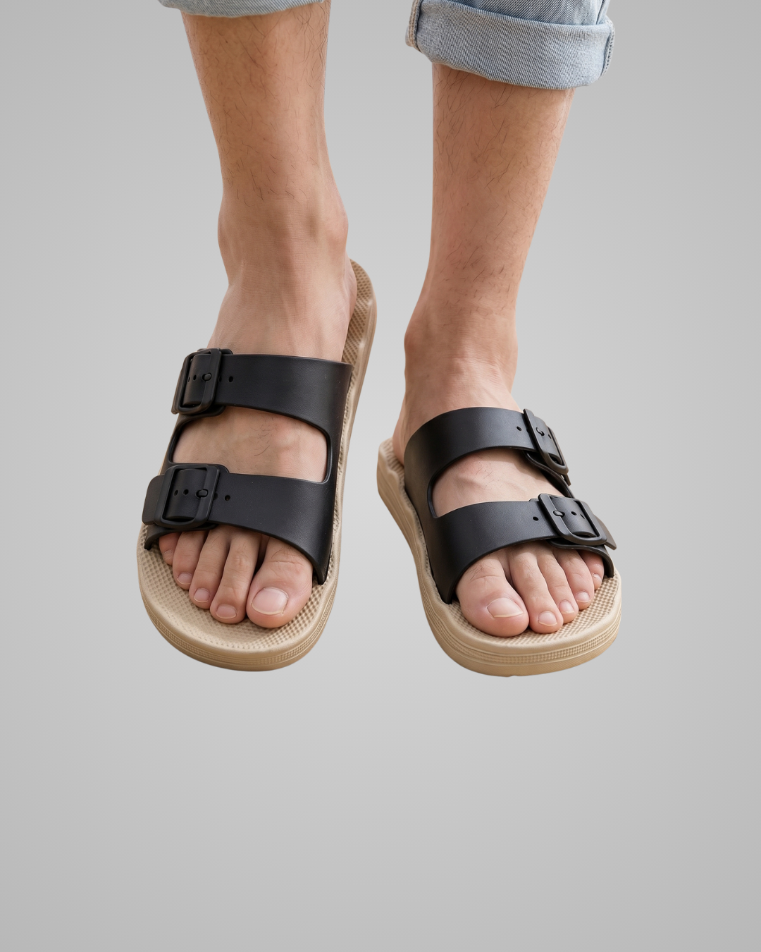 Black sandals with brown soles worn by a person on a gray background