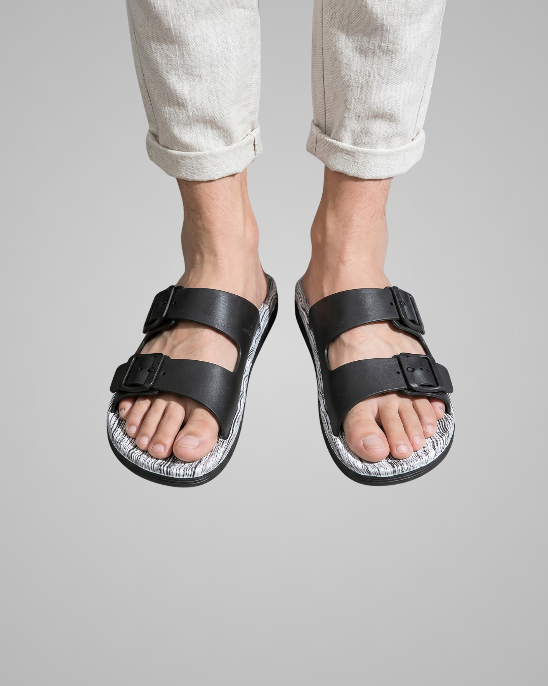 White sandals worn with light-colored pants on a gray background