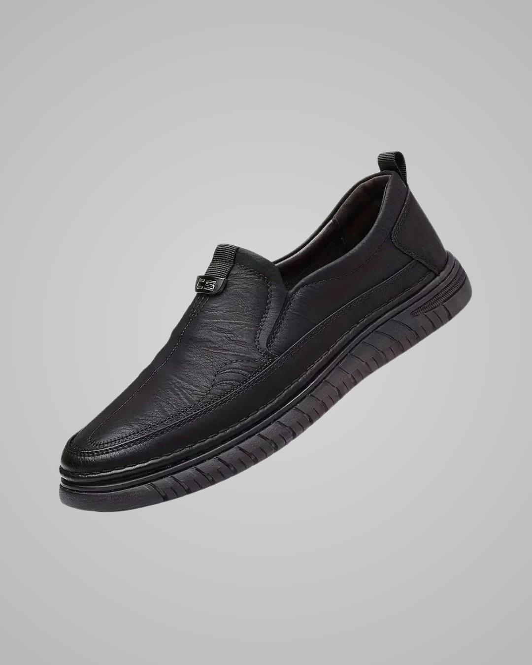 A single black slip-on shoe with a textured leather upper and a thick, treaded sole, shown against a solid gray background.