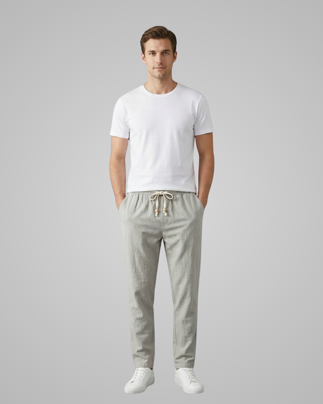 Man wearing a white t-shirt and light gray pants on a plain background