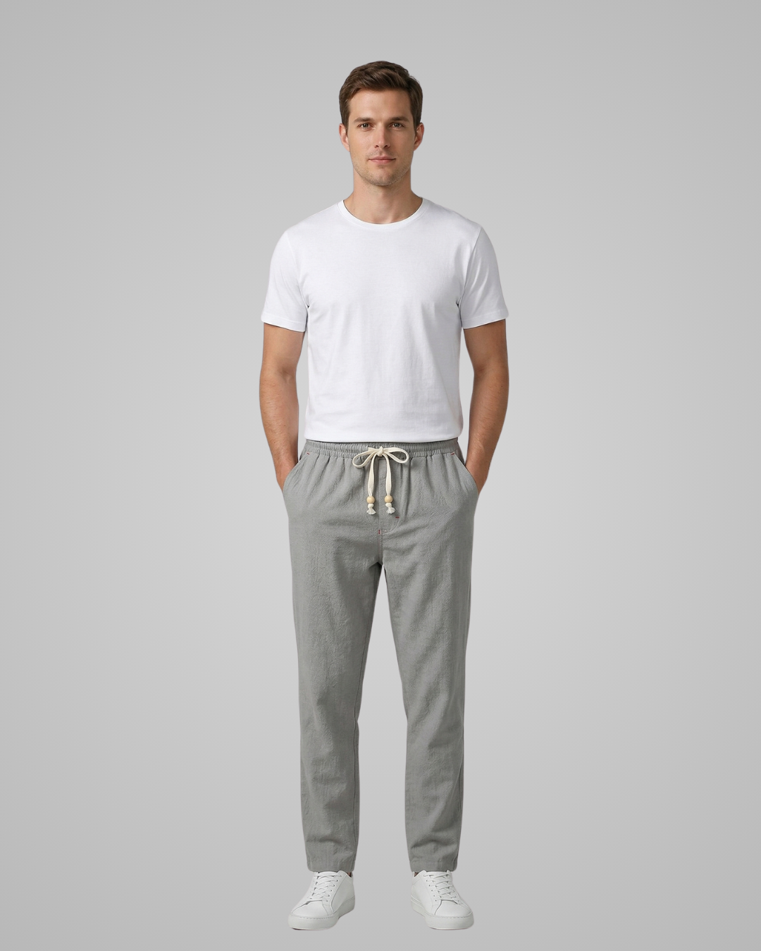 Man wearing a white t-shirt and gray pants on a gray background