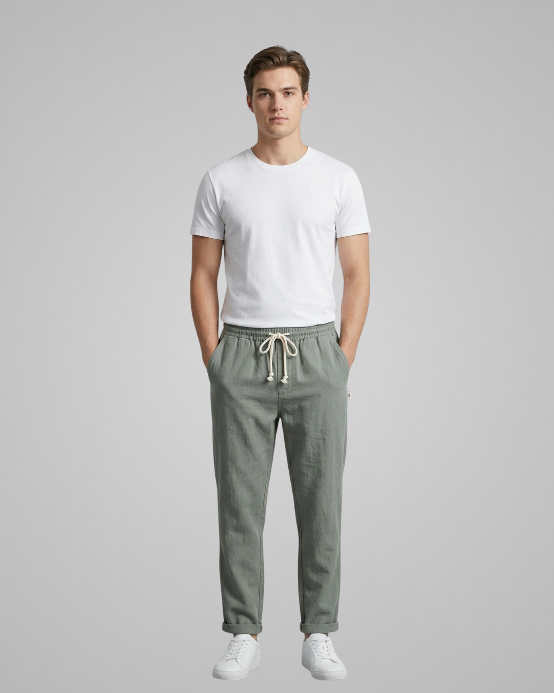 Man wearing a white t-shirt and green pants on a gray background