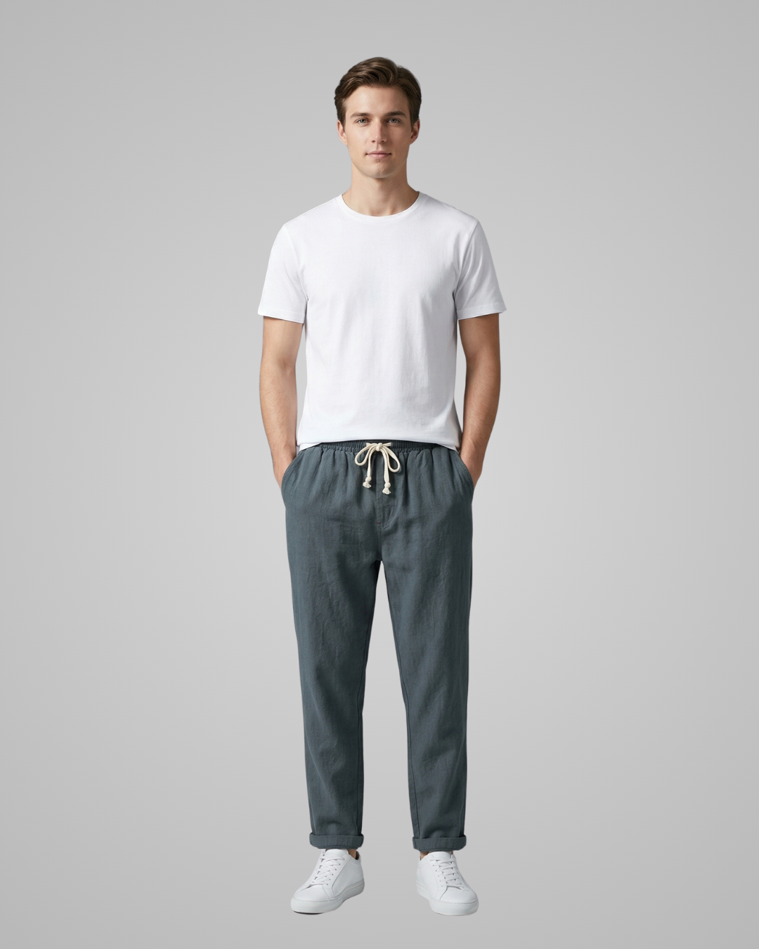 Man wearing a white t-shirt and gray pants on a plain background
