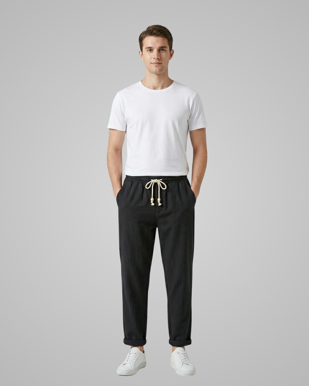 Man wearing a white t-shirt and black pants on a gray background