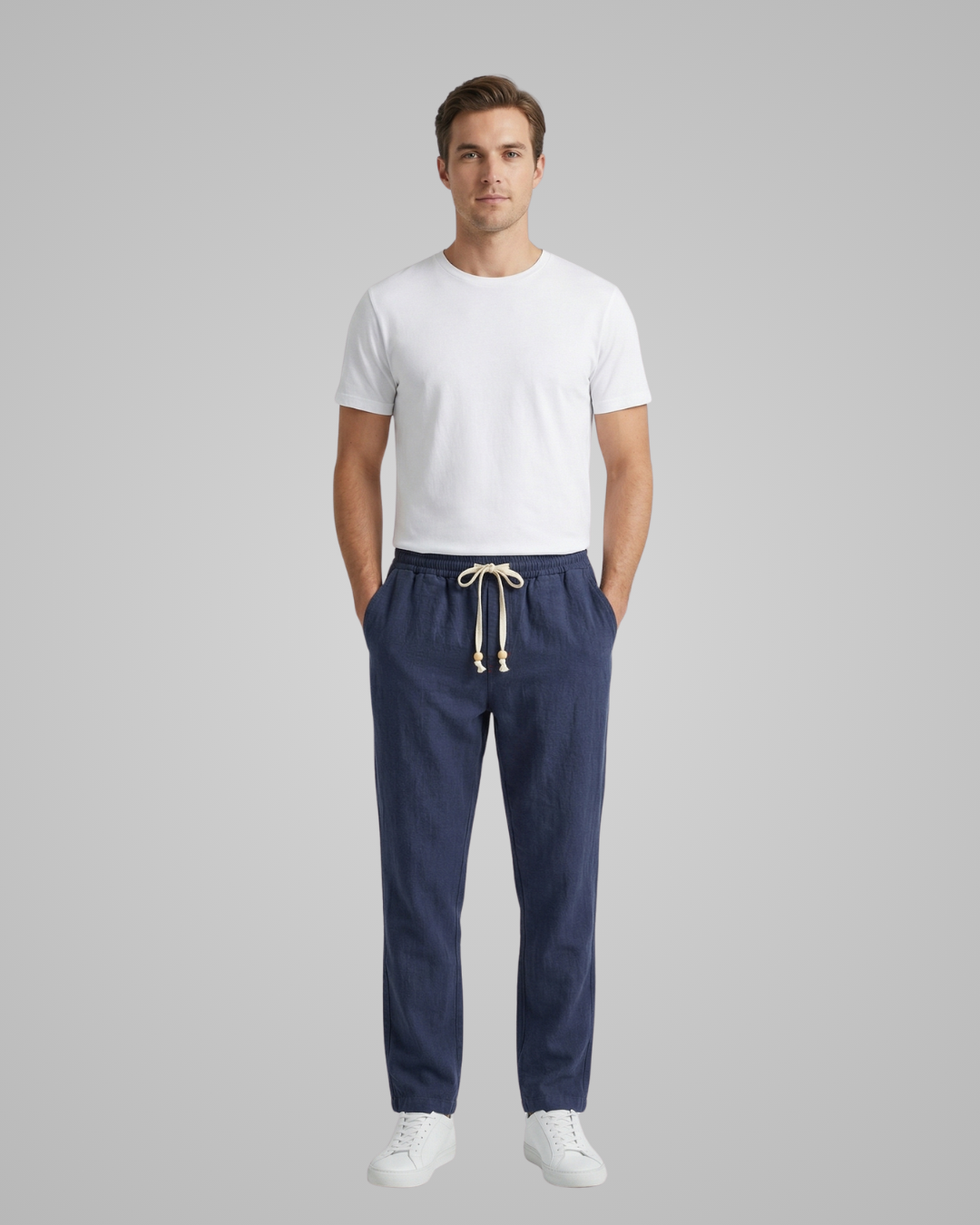Man wearing a white t-shirt and navy pants on a gray background