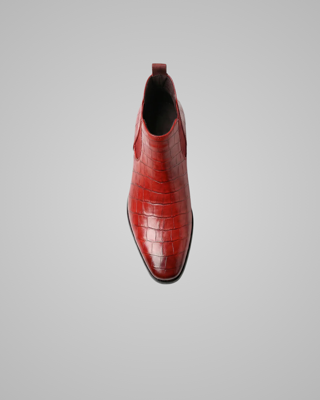 Red leather boot with crocodile pattern on a gray background
