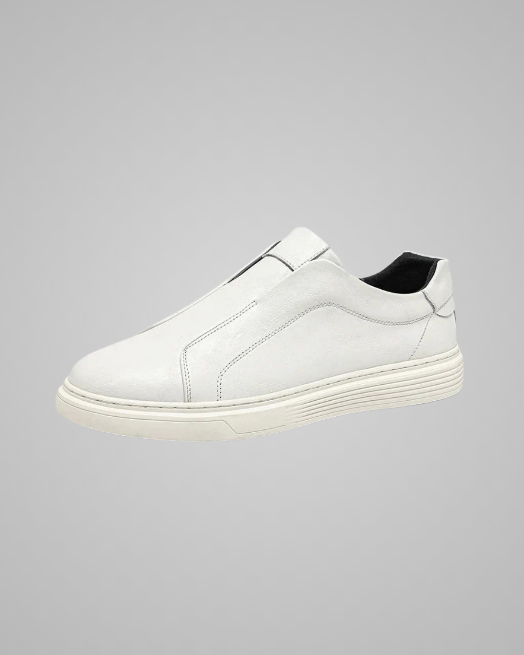 A white leather slip-on sneaker with a thick, ridged white sole and a black interior lining, shown from a side profile on a solid gray background.