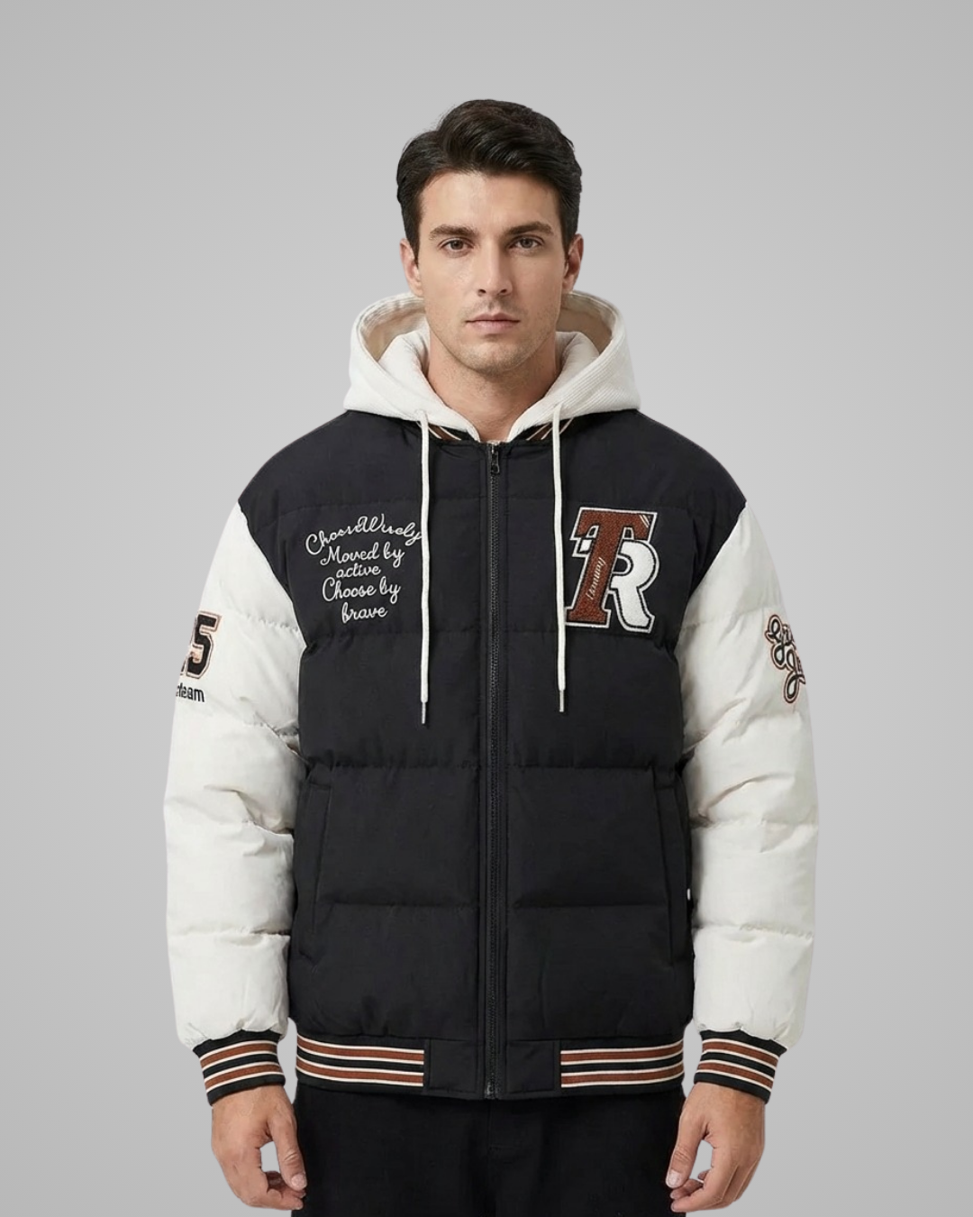 Man wearing a black and white varsity jacket with a logo on a gray background